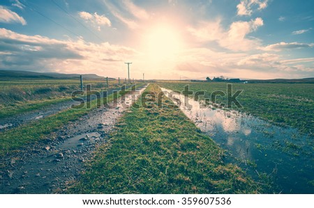 The sun setting over a remote farm. The image has added grain and styling.
