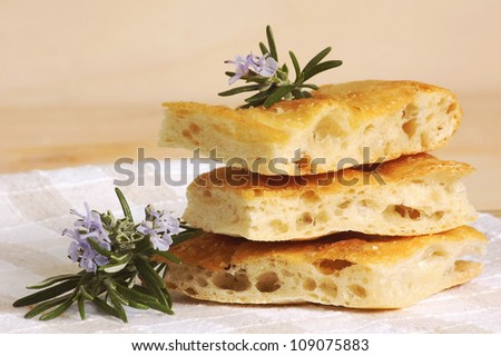 Pieces of italian bread called focaccia and fresh herb rosemary close up.Italian snack.Artisan bakery.
