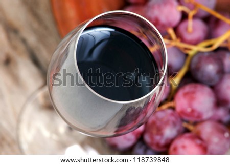 Glass of red wine closeup and purple grapes on rustic wood background.Alcohol,wine making.