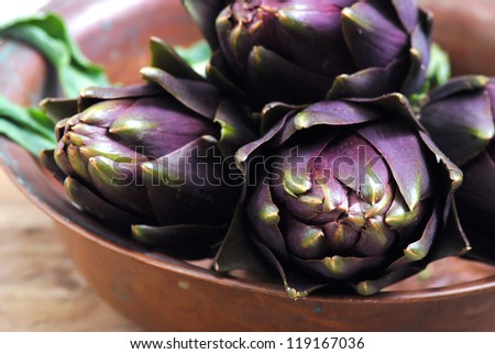 Raw purple artichokes in rustic background.Healthy eating, natural organic food concept.Fresh vegetables background.