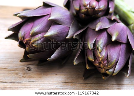 Closeup of fresh purple artichokes in rustic white wood background.Healthy eating, healthy lifestyles, natural bio food concept