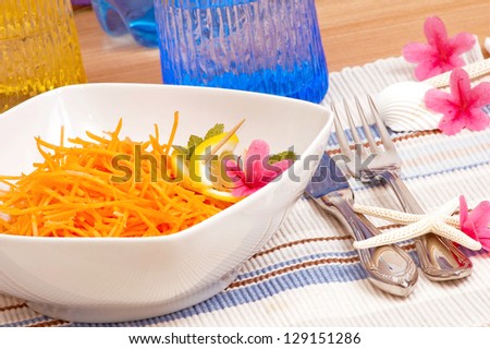 Carrot salad decorated with lemon and pink flowers closeup.Healthy, light,raw food.Dieting concept.