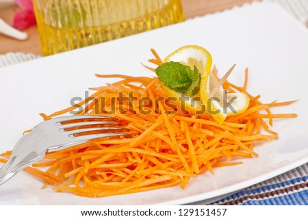 Carrot salad close up in white plate decorated with lemon. Raw, healthy food.