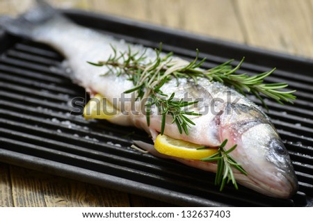 Raw seabass fish on grill.Fish cooking on a grill with aromatic herbs.Fresh seafood.
