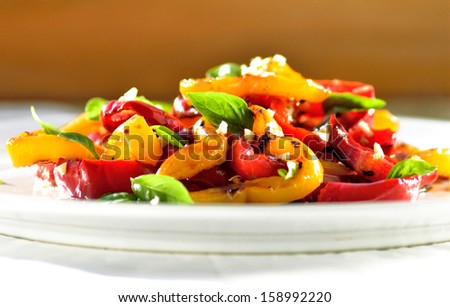 Plate of roasted vegetables, sweet red and yellow peppers with basil.Light, healthy, vegan mediterranean salad.
