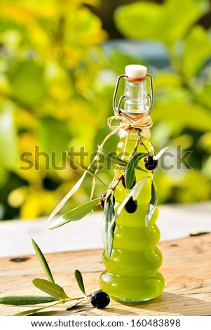 Bottle of olive oil and branch of black olives on wood rustic table over nature background.Mediterranean diet food concept.