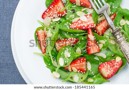 Spring salad spinach leaves, strawberries, almonds and sesame seeds, top view.Light, healthy, veg food concept.
