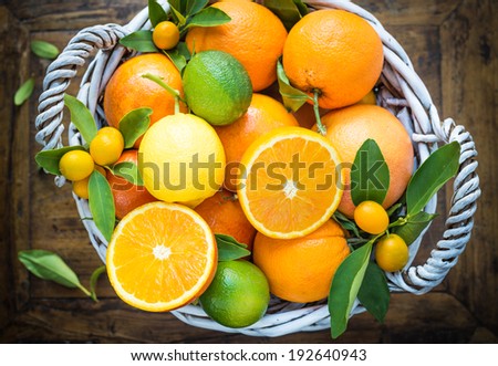 Citrus fruits in basket on rustic wood background.Oranges, limes, grapefruit, lemon,kumquats.