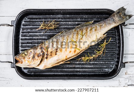 Fish on grill. Grilled sea bass fish with herbs.