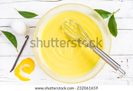 Pastry cream on white wood background. Preparation of custard pastry cream in a bowl, top view. Ingredient patisserie.