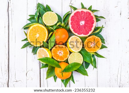 Fresh fruits heart on white wood background.Mixed citrus fruits.