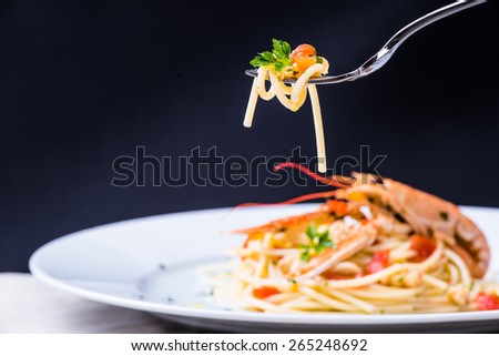 Plate with seafood spaghetti pasta on fork.Italian restaurant menu plate, noodles with prawns, langoustines, lobster.Italian food background.