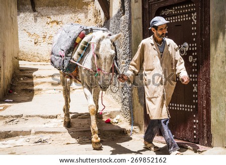 FEZ, Marocco, May 26, 2014: Unidentified Arabic man with horse in old Medina narrow street of Fez in Morocco.Fez is a historic city listed in UNESCO. May 26, 2014,Fez, Morocco.