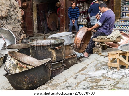 FEZ, Morocco, May 24, 2014:Artisan man pounding copper pot in old Medina souk, Seffarine place, metal souk square of Fez.Fez is a historic city listed in UNESCO. May 24, 2014,Fez, Morocco.
