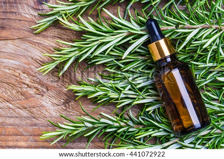 Rosemary oil bottle on wood background.Essential oil, natural remedies.