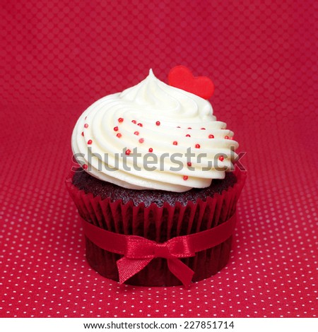 Chocolate cupcake cream white tie red bow ribbon  on a red background. Red hearts for love.