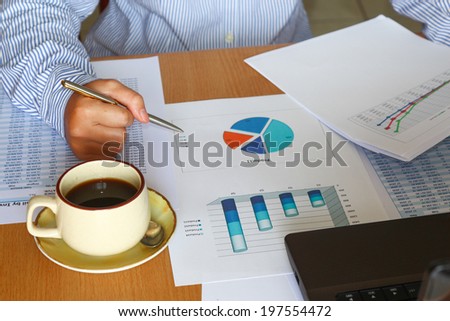 forecasting and analyzing sales charts and graphs report with coffee cup