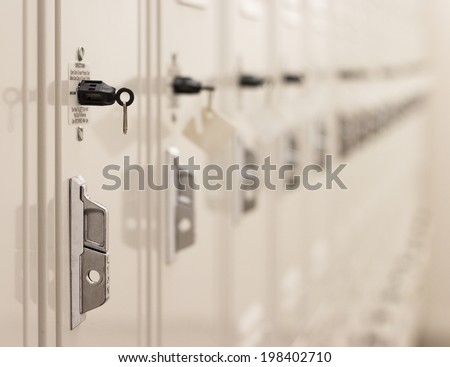 row of metal lockers with keys for safekeeping of valuables and personal clothing in a club or school with shallow dof on a receding row of lockers