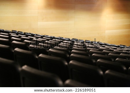 Bank of empty seats in an auditorium for a live stage performance with spotlights shining through the smoky atmosphere