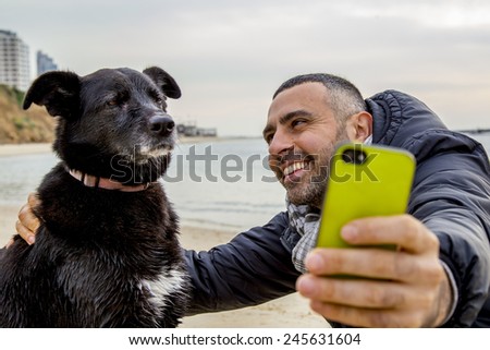 Tel-Aviv - January 19,2014: Man helping his grumpy dog friend to take a social media selfie image using a smartphone
