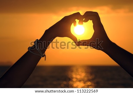 Men and women made ??a heart shape. heart shape made with the couple\'s hands at sunset