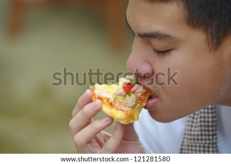 Asian boy eating pizza Thai boy eating pizza with greenery background