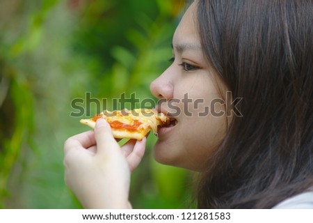 Thai girl eating pizza. Thai girl with white skin eating pizza with a green background.