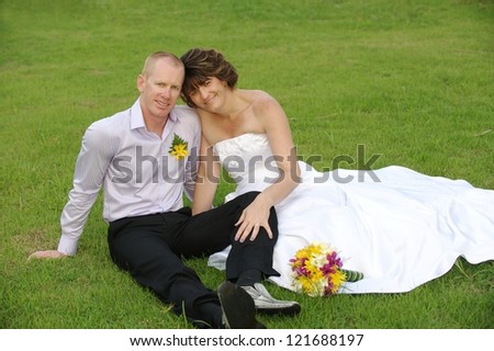 Bride and groom sitting on the grass Married couple sitting on the floor grass and smiling fully happy