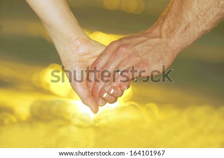 hand in hand of the couple with sunset