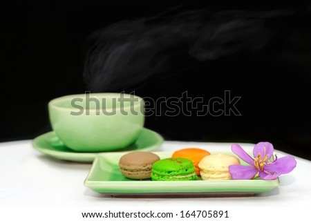 beautiful color of macarons with hot smoke rising from a cup of tea.