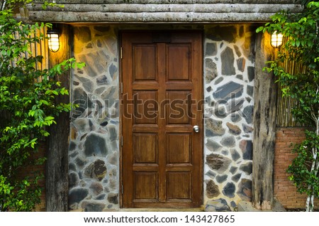 Front wooden door of residence, surrounded by nature in evening