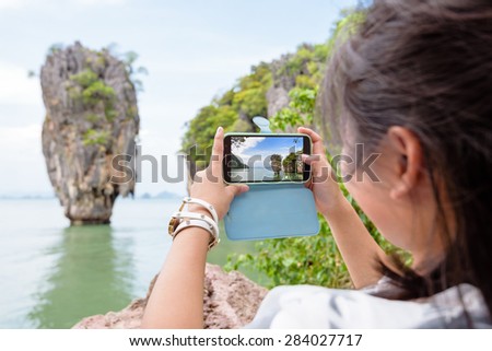 Women tourist he is shooting a beautiful scenic view by mobile phone at Khao Tapu or James Bond Island in Ao Phang Nga Bay National Park, Thailand