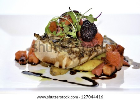 Cooked chicken breast atop baby potatoes topped with micro greens, berries, and sauces with balsamic vinaigrette