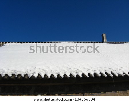 Layer of snow on a roof of the house in the spring