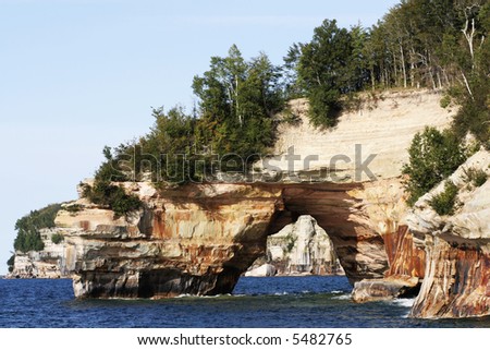 A rock with a hole above the lake in pictured rocks park.