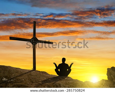Silhouette of a man practicing yoga on a mountain top at sunset