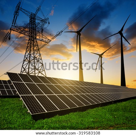 Solar panels with wind turbines and electricity pylon at sunset. Clean energy concept.