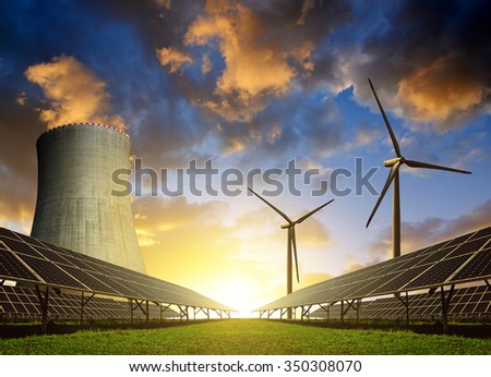 Solar energy panels, wind turbines and nuclear power plant at sunset.