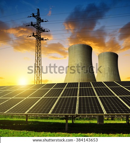 Solar energy panels, nuclear power plant and electricity pylon at sunset.