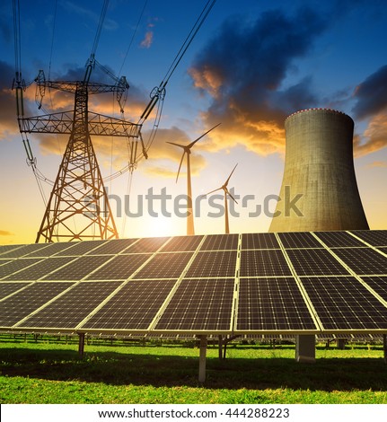 Solar panels in the background nuclear power plant, wind turbines and electricity pylon at sunset. Concept of energy resources.