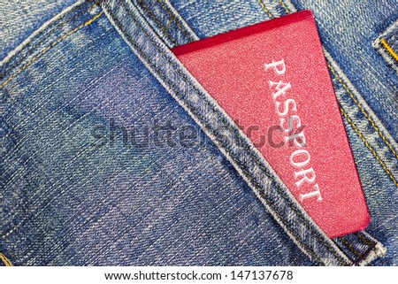 Red passport in blue jeans back pocket