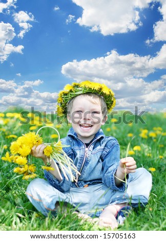 Happy kid with diadem and dandelions on meadow