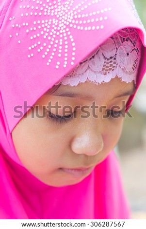 little muslim girl in pink hi jab reading a book
