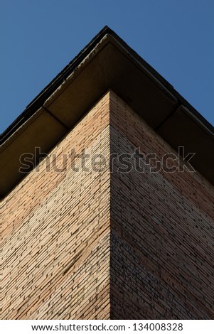 Brick corner of a house. One side in the shadow. Border between dark side and light side in the middle of the house.