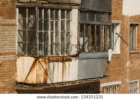 Old balcony with rust stains and rotten windows in the old house