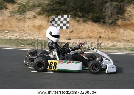 The winning go kart doing a lap of honour with the chequered flag