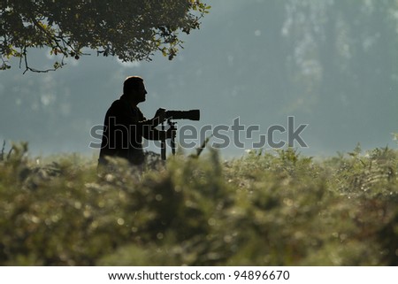 Silhouette of a wildlife photographer in an outdoor park in winter.