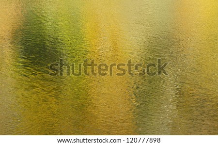 Abstract golden yellow water surface texture with green areas.