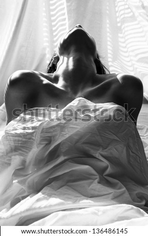 Naked woman under blanket in studio