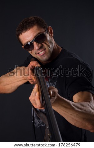man with gun and sunglasses smirks